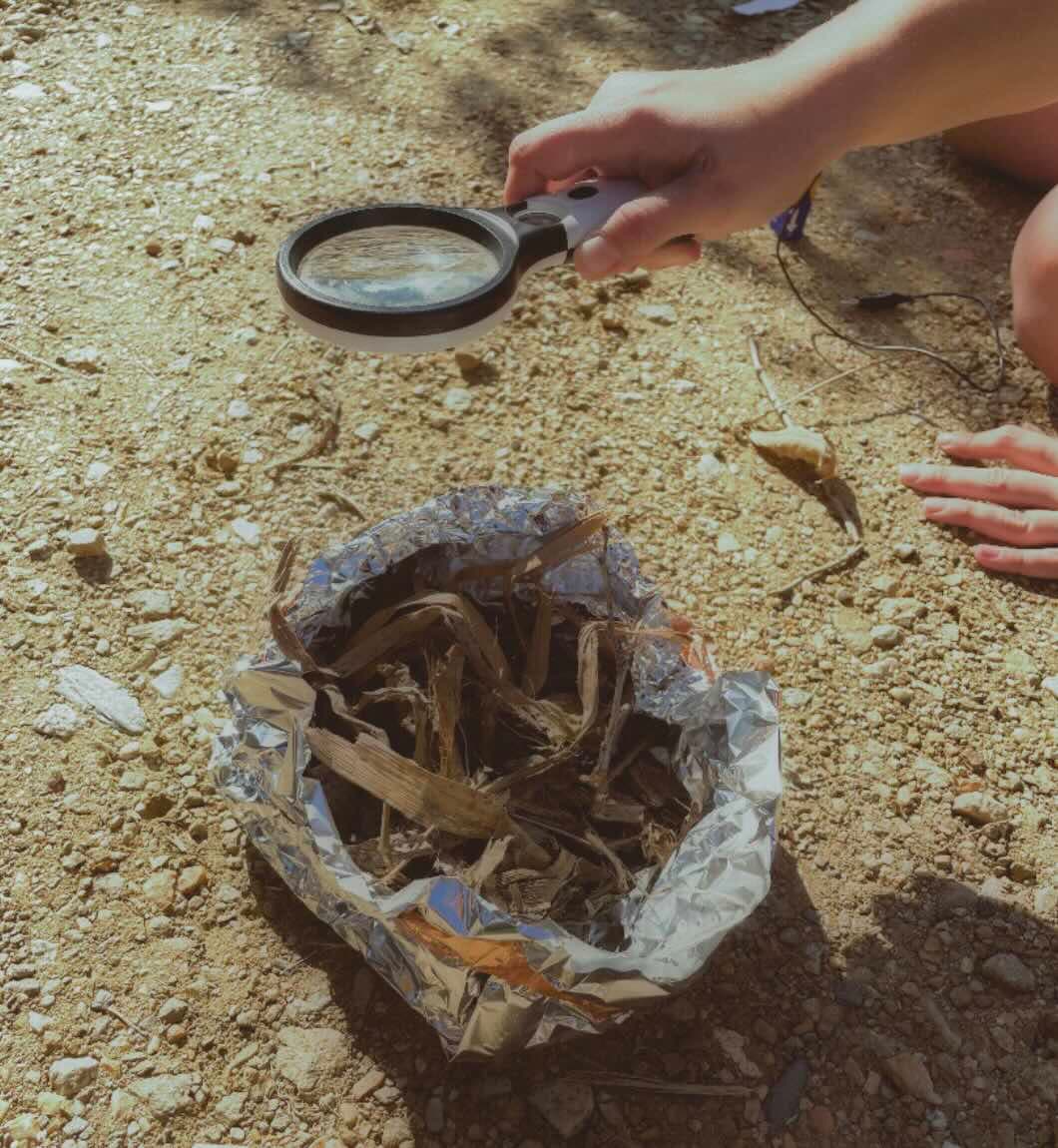Person trying to make fire with a magnify glass.